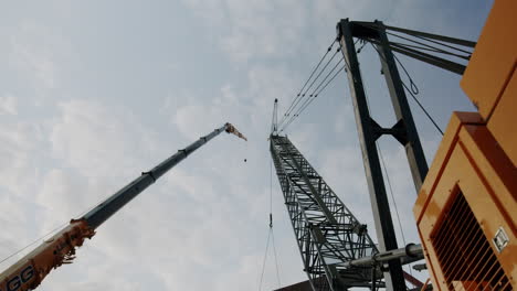 large cranes on a construction site against a cloudy sky