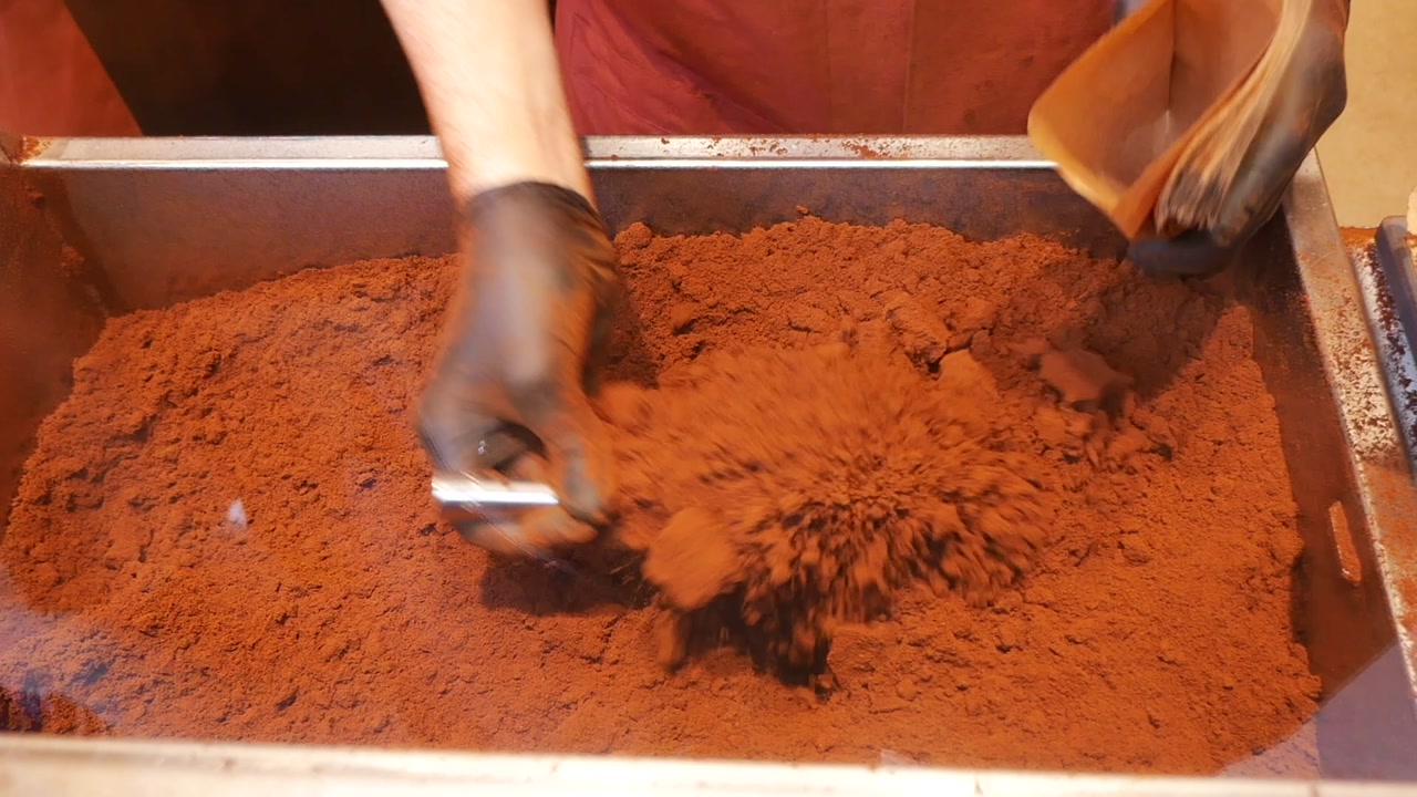 Worker Filling a Bag with Cocoa Powder in a Shop
