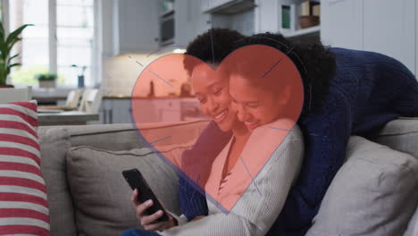animación de corazón rojo sobre dos mujeres usando un teléfono inteligente
