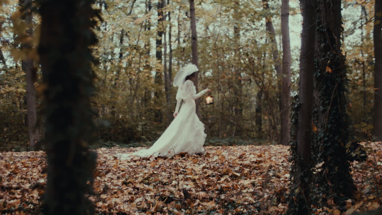 Donna misteriosa in abito bianco con lanterna in una foresta autunnale