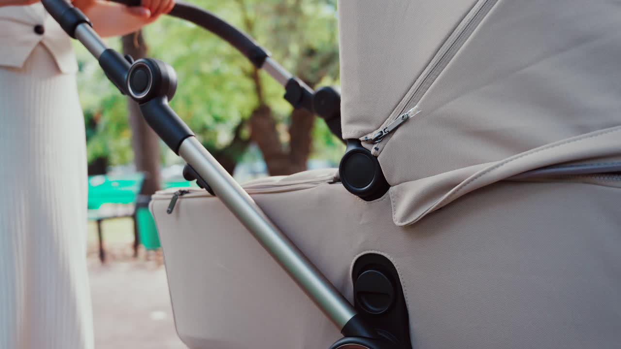 Young woman walking in the park with a baby stroller on a sunny day
