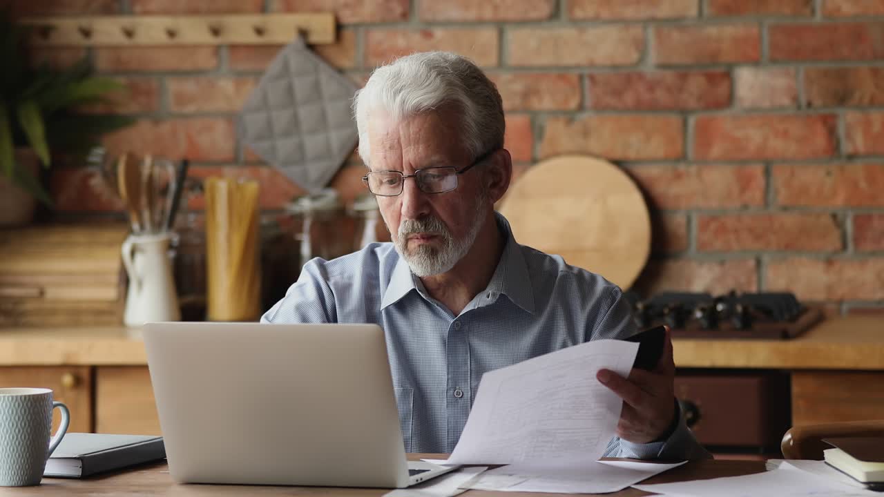 hombre maduro de sesenta años concentrado planeando el presupuesto del hogar.