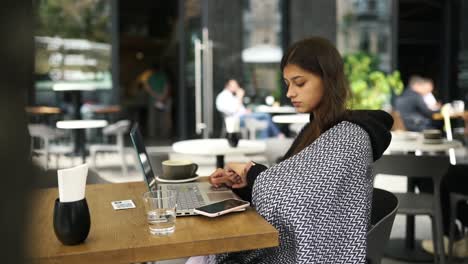 mujer trabajando en una computadora portátil en un café