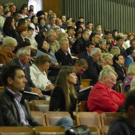 crowd of people to sitting and listening in a large hall
