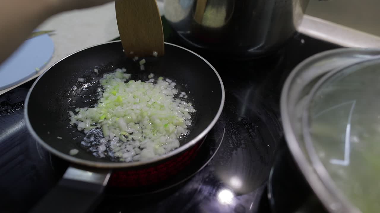 Fried chopped onion in hot boiling oil. Closeup of frying pan, cooking onion