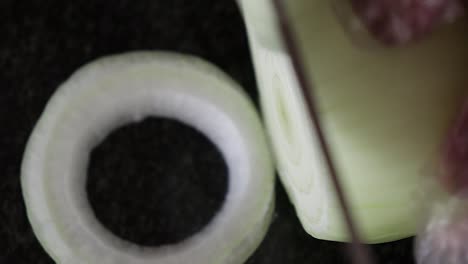 a close up, top shot of an onion being cut into rings