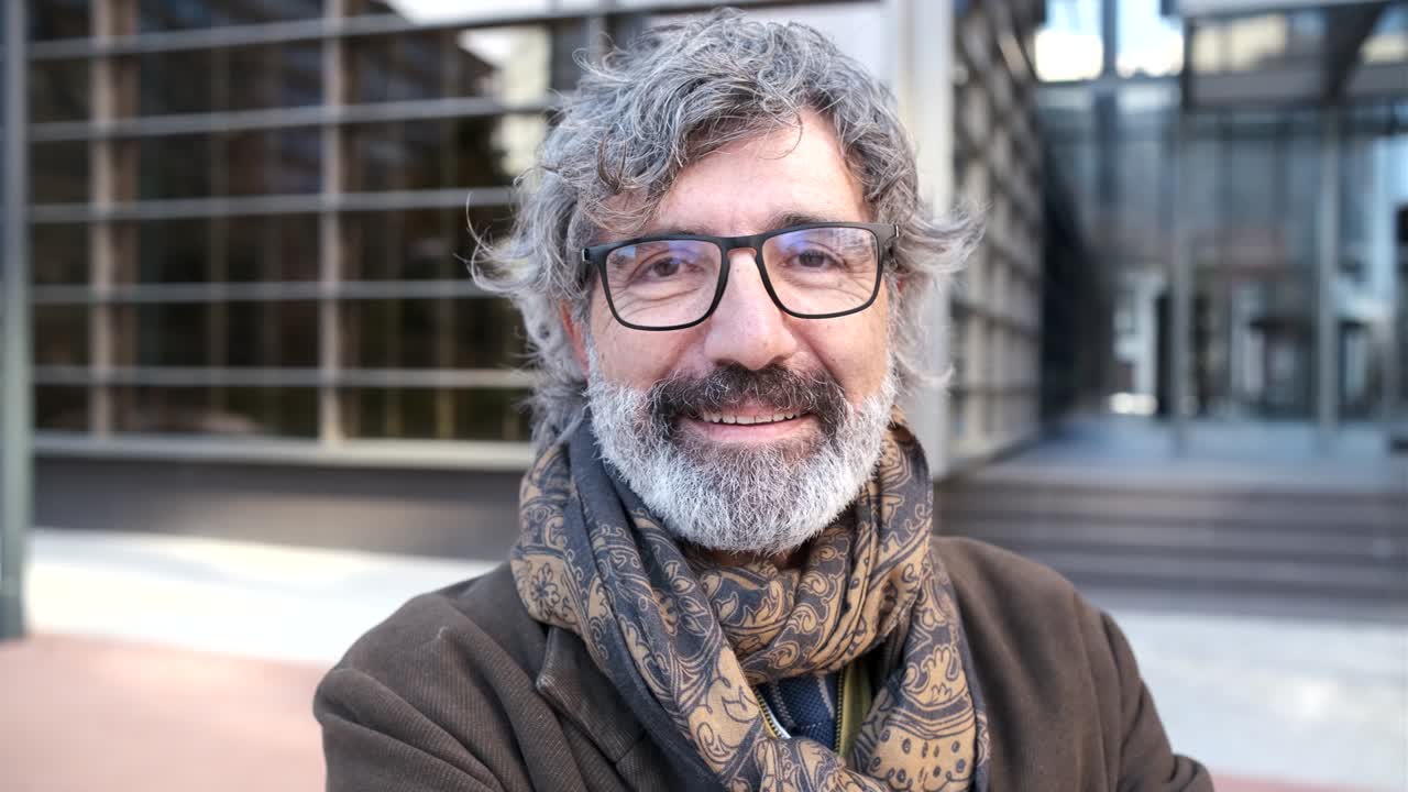 Middle-aged man looking at the camera while posing in the financial district with an office building on background.