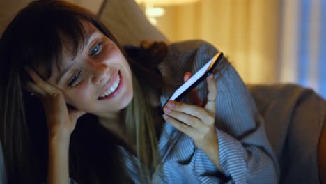 caucasian woman smiling and using smartphone at home