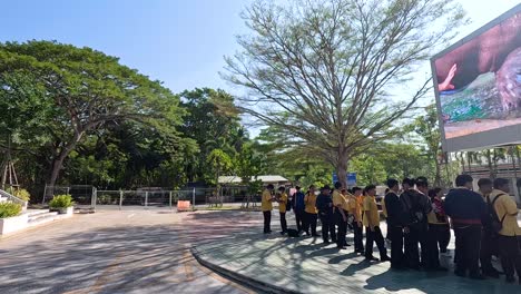 people gather under a large outdoor screen