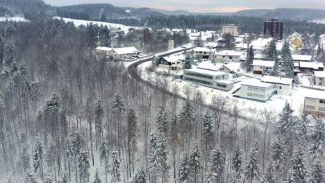 Wundervoller-Tag-In-Der-Wintersaison,-Mit-Einer-Drohne-über-Schneebedeckten-Bäumen-Aufsteigend,-Mit-Blick-Auf-Eine-Kleine-Stadt-Vor-Hügeln