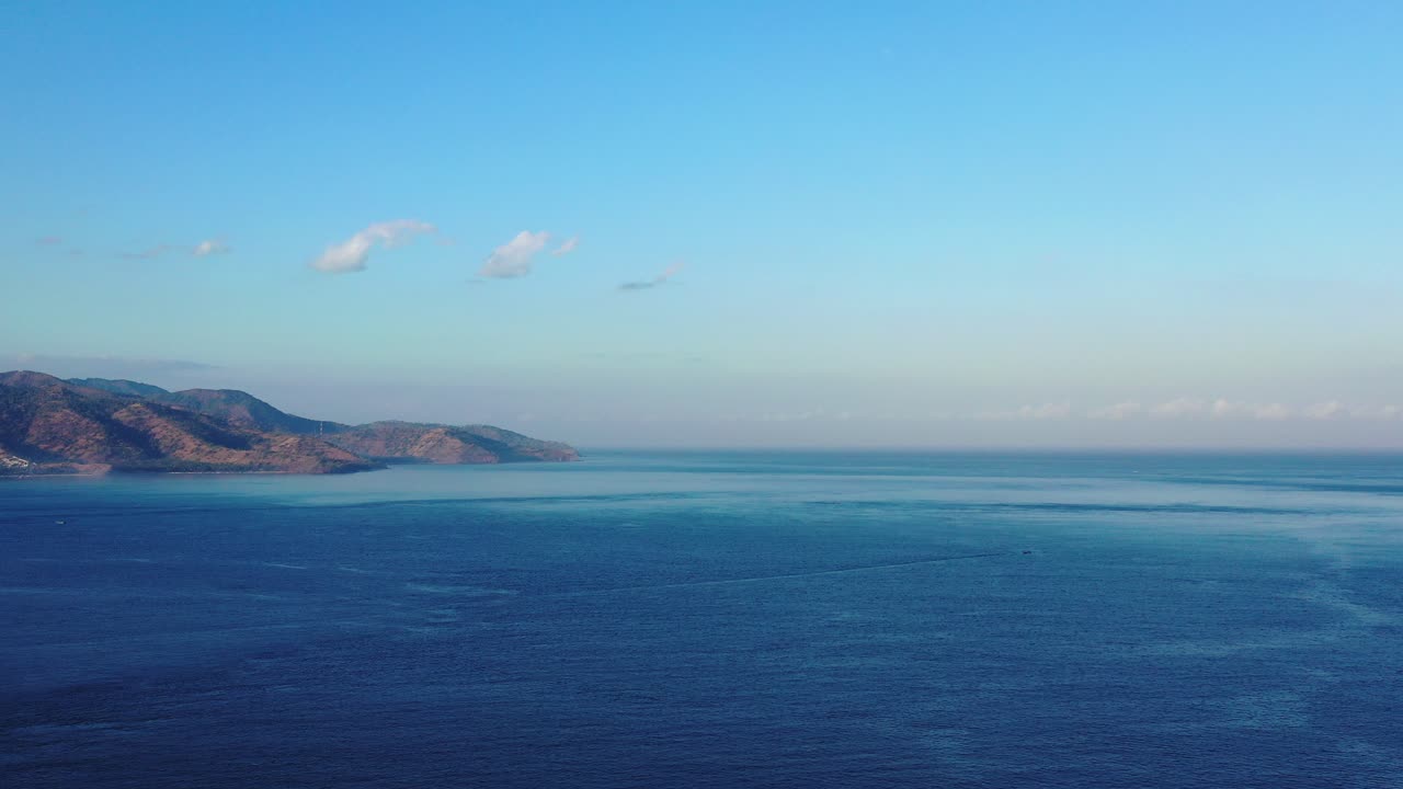 Aerial view of the beautiful blue ocean seas, mountains from a tropical island, and the clear blue sky