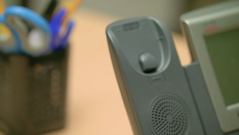 close-up, static shot of a landline phone being answered