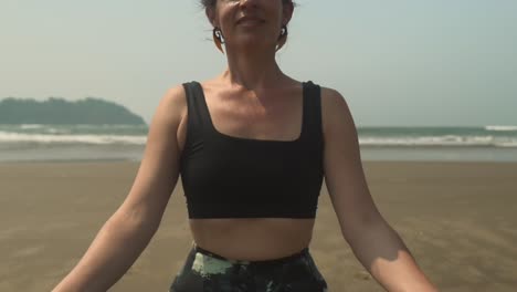 Meditating-brunette-Caucasian-woman-on-beach-practising-mindfulness-inner-peace