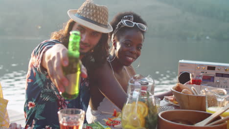 portrait of joyous multiethnic couple at lake party with friends