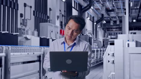 asian male professional worker standing with his laptop with water production in bottling factory, work continuously