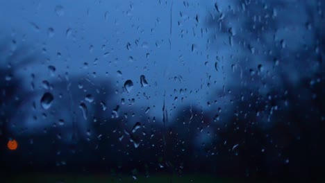 rainy storm droplets at night, moody weather fall down window glass closeup bokeh