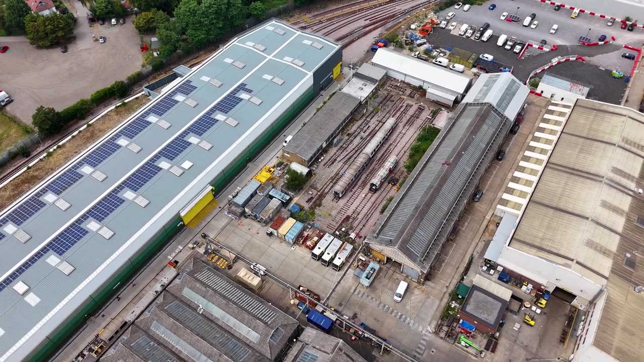 Officine industriali con pannelli solari sul tetto e capannoni aperti sui lati riempiono un complesso ingegneristico accanto alla ferrovia.