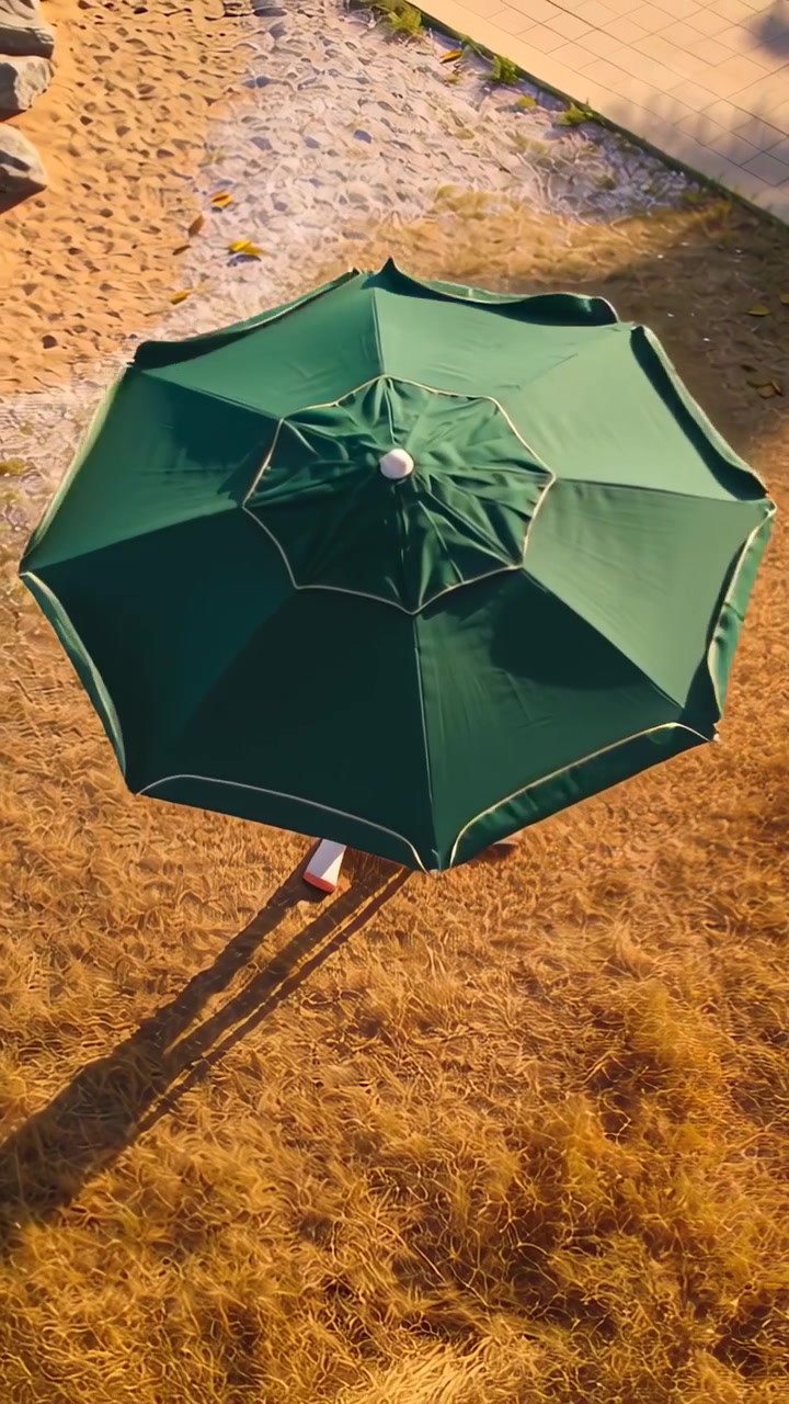 Video verticale: Telecamera che si muove mostrando un ombrellone verde che si sposta sull'erba secca in riva, mostrando una scarpa rossa
