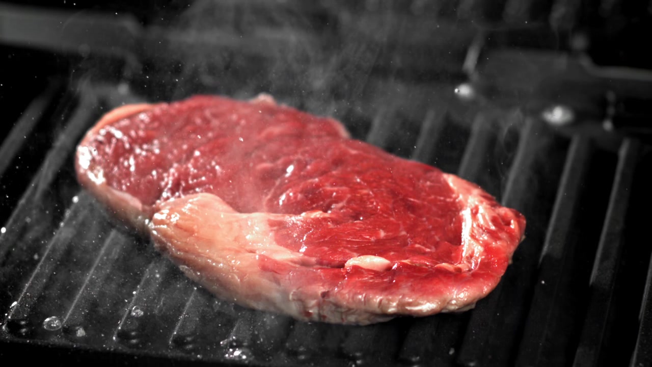 Raw Steak Sizzling on a Hot Grill