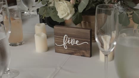 wedding dining with a view of wooden decorations surrounded by candles, flowers and tall glasses