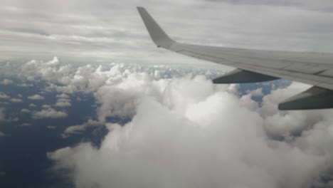 vista desde la ventana del avión de la izquierda, vista de ala sobre cúmulos blancos con el océano azul debajo y nubes cirros más allá