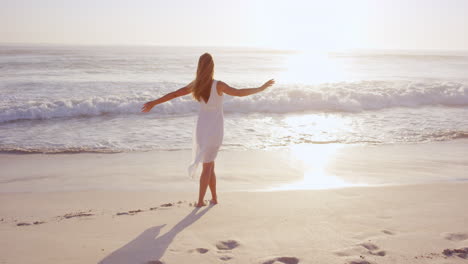 Mujer-Feliz-Libre-Disfrutando-Del-Atardecer.-Hermosa-Mujer-Vestida-De-Blanco-Abrazando-El-Brillo-Dorado-Del-Atardecer-Con-Los-Brazos-Extendidos-Y-La-Cara-Levantada-En-El-Cielo-Disfrutando-De-La-Paz,-La-Serenidad-En-La-Naturaleza