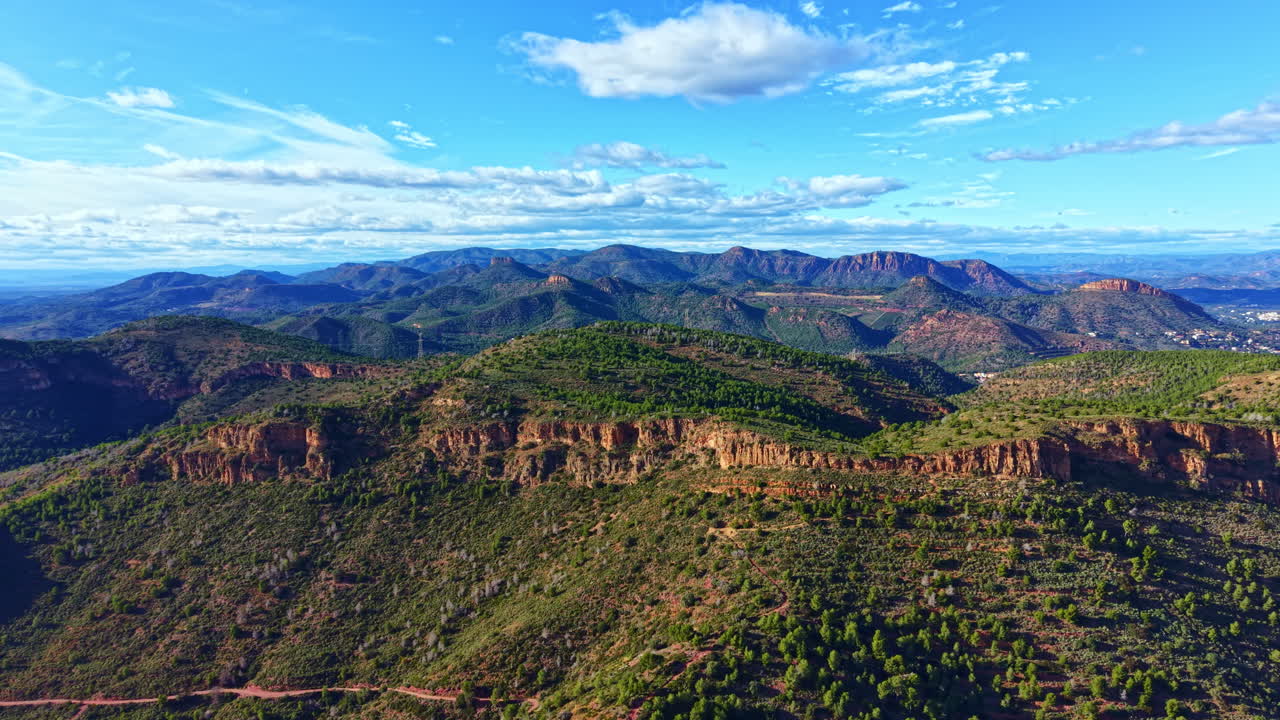 Un suggestivo paesaggio montano con alberi verdi e colline rocciose sotto un cielo blu con nuvole durante il giorno in un ambiente naturale.