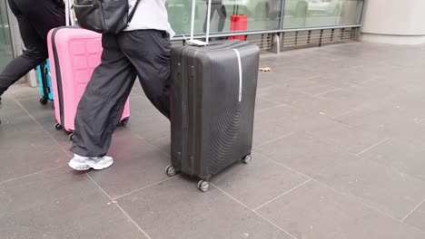 people moving luggage outside a building entrance