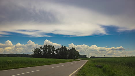 timelapse shot of car passing by along rural road with dark clouds passing by during evening time
