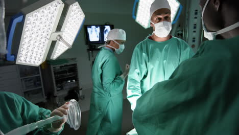 diverse male and female surgeons operating on patient in operating theatre at hospital, slow motion