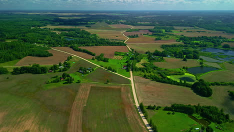 aerial drone pullback from y shaped intersection of dirt roads above farmland fields