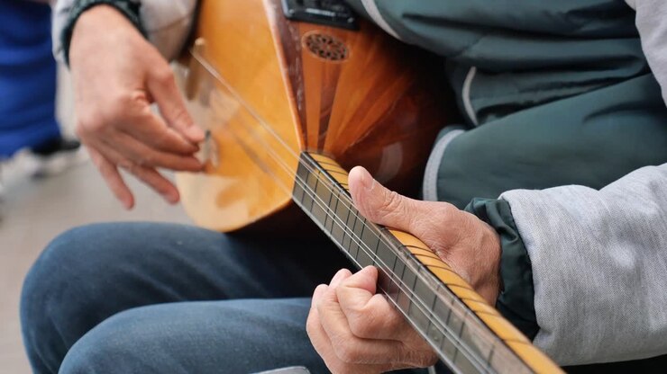 A man plays the saz, a traditional Turkish string instrument.