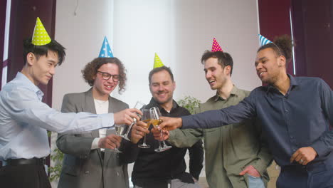 Glückliche-Multiethnische-Gruppe-Männlicher-Kollegen,-Die-Champagnerglas-Toasten-Und-Dann-Auf-Der-Büroparty-In-Die-Kamera-Schauen