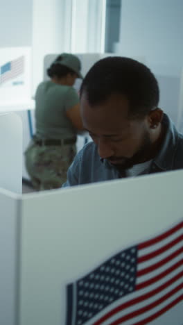 African-American-man-comes-to-vote-in-booth-in-polling-station-office.-National-Elections-Day-in-the-United-States.-Political-races-of-US-presidential-candidates.-Civic-duty.-Slow-motion.-Dolly-shot.