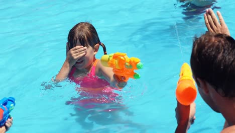 Familia-Feliz-Haciendo-Tiroteos-De-Agua-En-La-Piscina