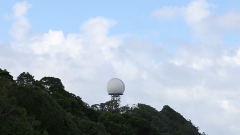 static view of a radar dome atop a forested hill