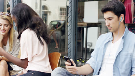 female friends sharing together using smartphone in urban cafe