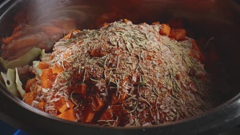 마른 바질, 후추, 파프리카 향신료가 야채 스튜 냄비에 추가되고 있습니다.