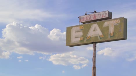 time lapse shot of clouds drifting past a sign saying eat