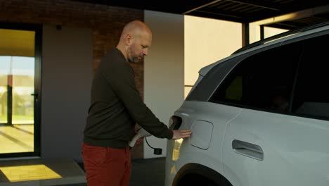 man charging electric vehicle at home