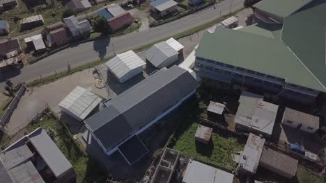 Low-aerial-flight-over-primary-school-in-African-township,-Knysna