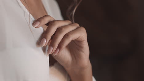 young woman hand adjusts white chiffon negligee in bedroom