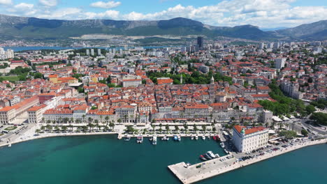 aerial view of split, croatia - historic old town with red-tiled roofs, riva promenade, and surrounding mountains in background. pullback shot