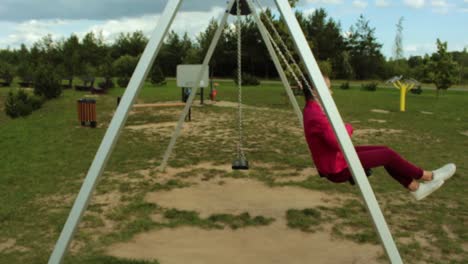 Girl-with-red-jacket-swinging-on-the-swing-set