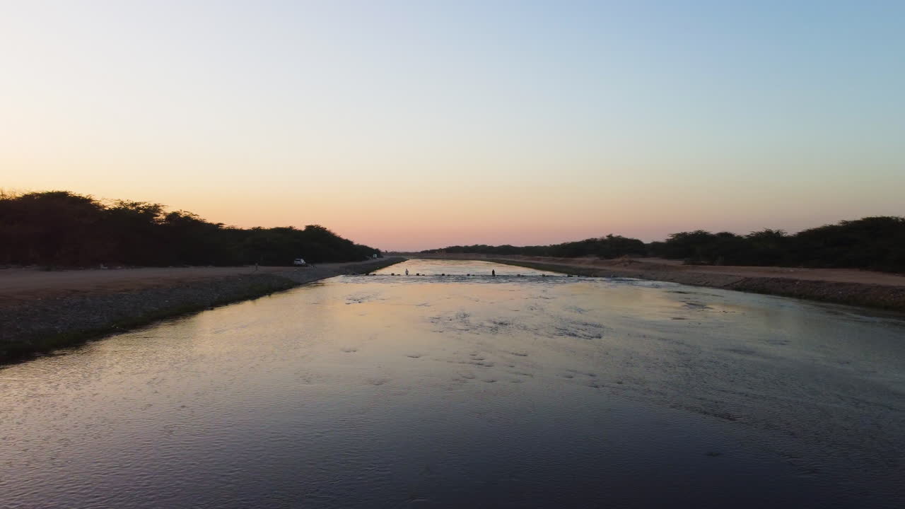 Aerial view rising over a shallow river, serene, sunny evening in Saudi Arabia