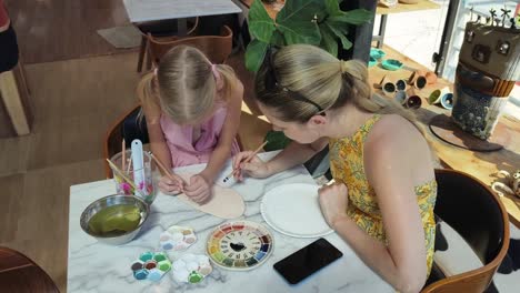 mother and daughter painting pottery