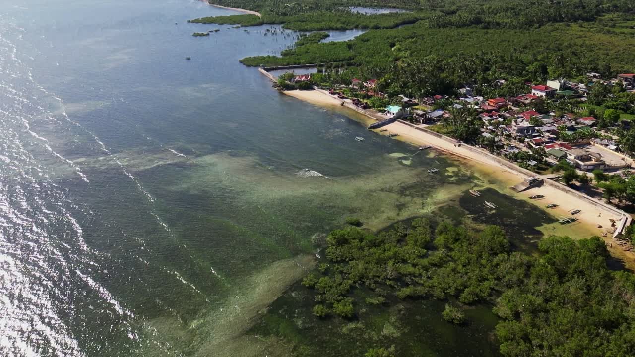 Picturesque view of the coastal village town Yocti with lush foliage and a transparent cove at Catanduanes, Philippines - aerial drone shot