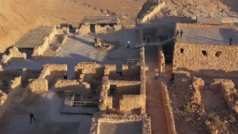 aerial view of the ancient masada fortress ruins with visitors exploring during sunrise or sunset