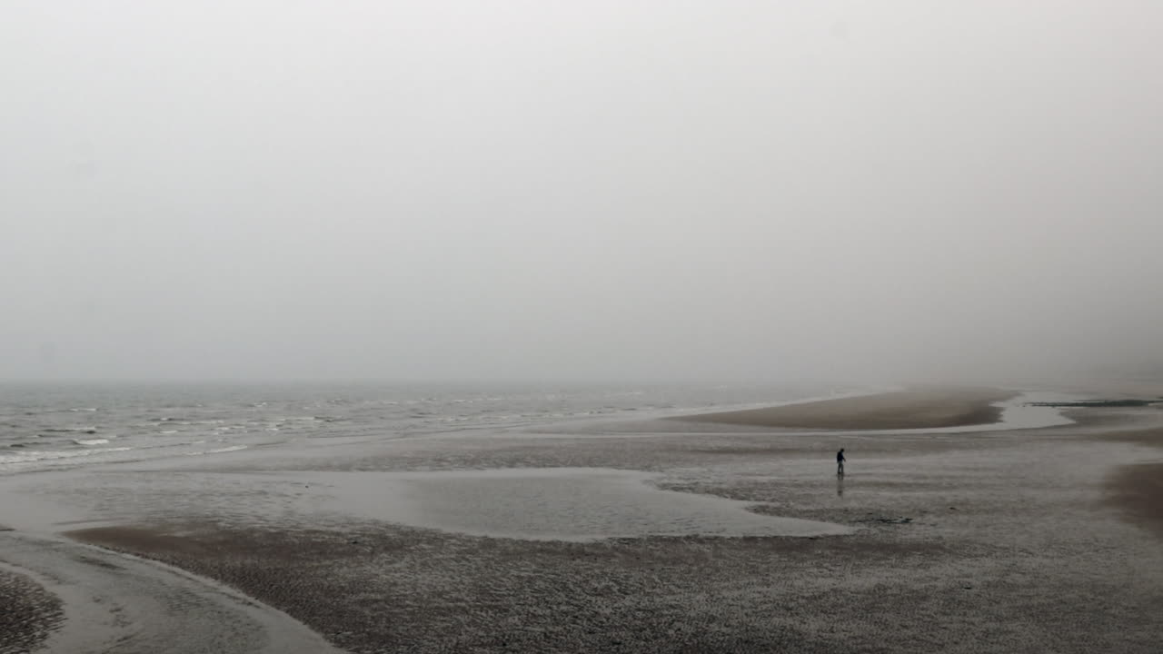 hombre caminando en la playa en un día de niebla en normandía