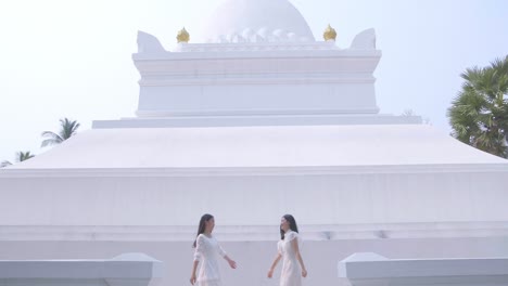 two asian girls holding hand and having fun on summer travel near the temple, slow motion